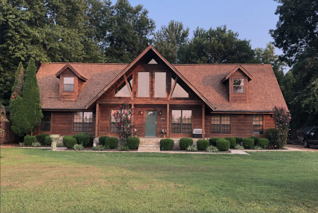 front view of the brown cabin, front door, and windows set in the woods